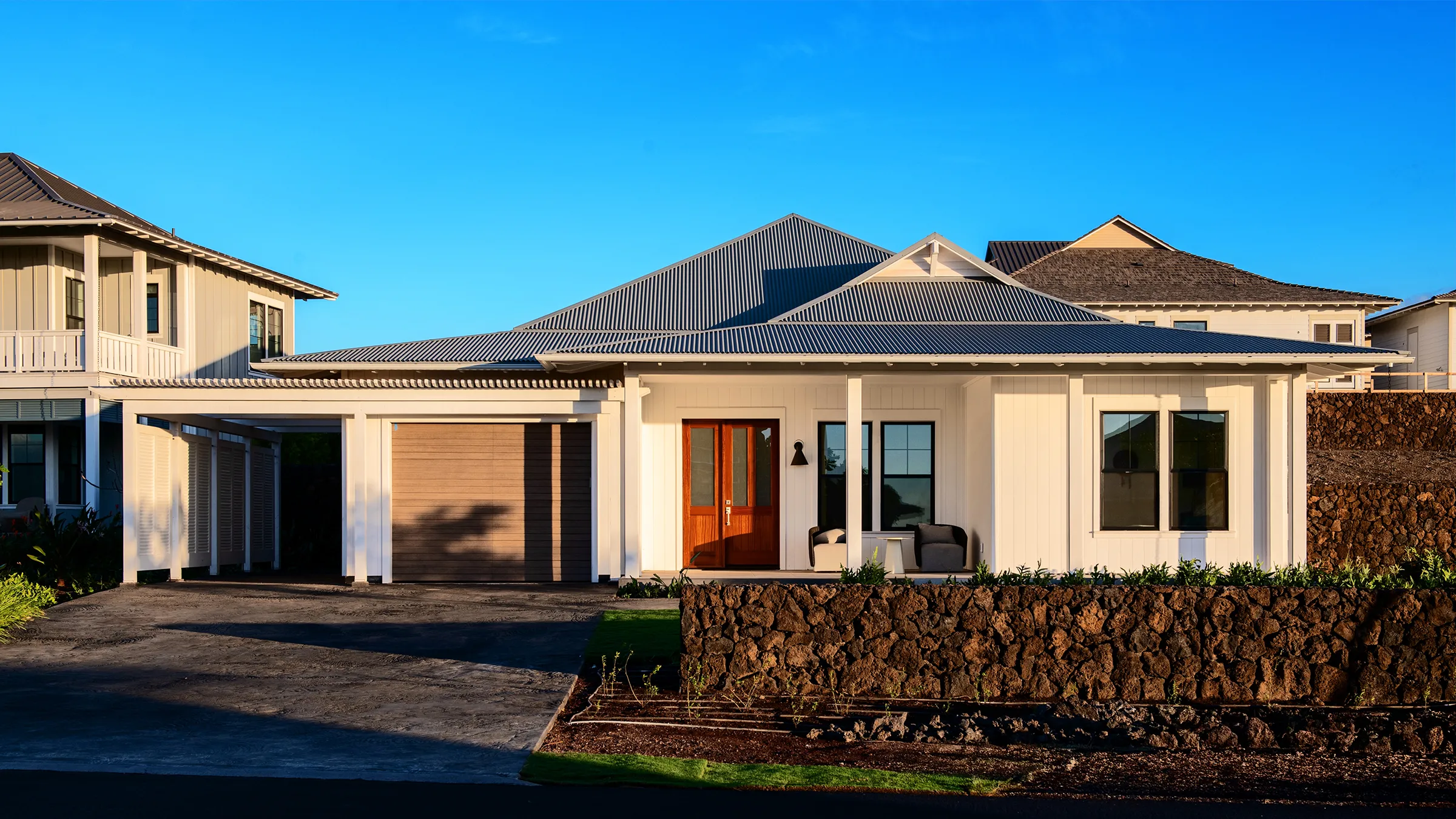 Two-story house with a wraparound porch surrounded by trees and greenery.